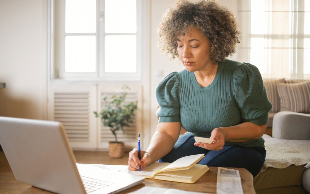 Woman working on laptop and taking notes about expat